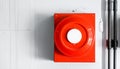 Red square fire alarm with a large white circular button on a wall device Royalty Free Stock Photo