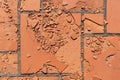 Red square floor tiles damaged by weathering or material defects. The surface is crumbling and the plates are disintegrating.