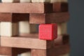Red square wooden cube standing among wooden blocks closeup