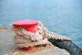 Red stand on the pier with a rope and tyre