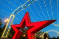 Red star close-up and LED garlands on alley in evening park Pobedy. Belgorod city.