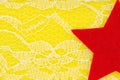 Red star with delicate lace textured material on bright yellow knit background