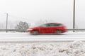 Red car, station wagon driving fast on the road in winter landscape, with snowy weather. Motion blur Royalty Free Stock Photo