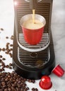 Red steel cup with coffee capsules and home espresso machine on white background with fresh aroma coffee beans Royalty Free Stock Photo