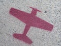 Red stenciled propeller airplane on sidewalk