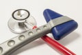 Red stethoscope and neurological reflex hammer with blue triangular head lie crosswise on white background on doctor workplace. Eq