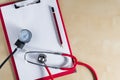Red stethoscope, tonometer and red pencil on a red clipboard. Top view. Right copy space. Medical device. Treatment, health care.