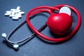 Red stethoscope and white pills and red heart on a blue tone background. Royalty Free Stock Photo