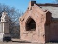 A red stone mausoleum in a cemetery