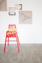 a red stool with some stuffed animals on it in front of a white wall