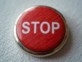 Red stop button resting on white textured surface Royalty Free Stock Photo