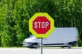 Red stop road sign in the foreground and blurred fast car in the background