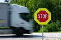 Red stop road sign in the foreground and blurred fast truck in the background