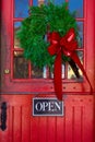 Store entrance door with open sign and Christmas wreath