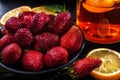 Red strawberries in a black plate, lemon slices and glass tea with lemon Royalty Free Stock Photo