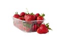 Red strawberries laying in big plastic transparent container and one big berry laying near the box isolated on white