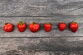 Red strawberries lined up against a dark wooden background