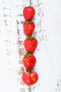 Red strawberries lined up on a white wooden background