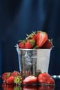 Red strawberries in a metal bucket closeup in a blue background. Multivitamin cocktail. Healthy lifestyle. Summer fresh taste.