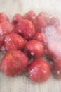 Red strawberry in drops of water and a cold rar in the defocus under the glass on a light wooden background