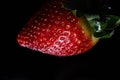 Red strawberry fruit close up skin texture on a black background Royalty Free Stock Photo