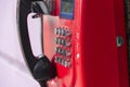 Red street payphone with round stainless steel buttons close-up.