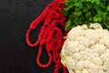 Red string bag, raw white cauliflower and fresh green parsley on black background. Eco friendly lifestyle. Zero waste Royalty Free Stock Photo