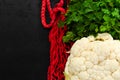 Red string bag, raw white cauliflower and fresh green parsley on black background. Zero waste concept. Flat lay Royalty Free Stock Photo