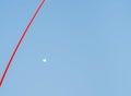 Red stripe dives blue sky with small white moon Royalty Free Stock Photo