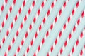 Red striped cocktail straws on pastel mint color as abstract joyful background, diagonal lines pattern.