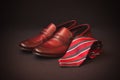 Red striped rolled necktie and brown men`s shoes. Selective focus Royalty Free Stock Photo