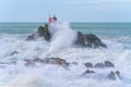 Red structure of beacon on North Rock ar base of Mount Maunganui with wild stormy sea crashing around and over it