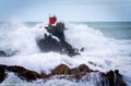 Red structure of beacon on North Rock ar base of Mount Maunganui with wild stormy sea crashing around and over it