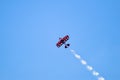Red stunt airplane in flight against blue sky