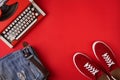 Red suede sneakers shoes, distressed jeans and typewriter on red background Royalty Free Stock Photo