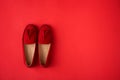 Red suede woman`s mocassin shoes over red background