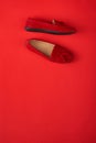 Red suede woman`s mocassin shoes over red background