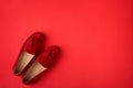 Red suede woman`s mocassin shoes over red background