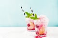 Red Summer cooling drink with ice, lime, raspberries and syrup on light background. Royalty Free Stock Photo