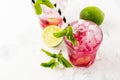 Red Summer cooling drink with ice, lime, raspberries and syrup on light background. Royalty Free Stock Photo