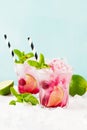 Red Summer cooling drink with ice, lime, raspberries and syrup on light background.