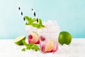 Red Summer cooling drink with ice, lime, raspberries and syrup on light background. Royalty Free Stock Photo