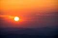 Red sun setting behind mountain and making clouds red Royalty Free Stock Photo