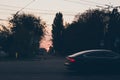 Red sun, silhouettes of trees and car rushes along evening road Royalty Free Stock Photo