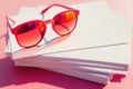 Red sunglasses on stack of paper with pink background, generative ai Royalty Free Stock Photo