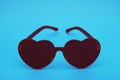 Red sunglasses in the shape of a heart on a blue background. Royalty Free Stock Photo
