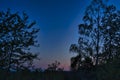 Red sunset and new moon in a beautiful sky. Beautiful background with trees in the foreground Royalty Free Stock Photo