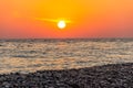 Red sunset on the sea beach. Soft sea waves and sea pebbles. Composition of nature Royalty Free Stock Photo