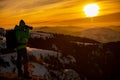 Red sunset and the silhoute of photographer enthusiast stay on cliff and thinking