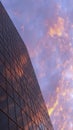 The red sunset of the sky with clouds is reflected in the glass of a typical high-rise building. Abstract vertical evening urban Royalty Free Stock Photo